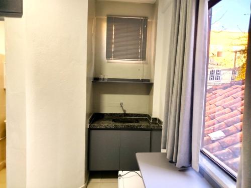 a small kitchen with a sink and a window at Vila Del Rei - Flat no Centro de São João Del rei in São João del Rei