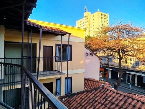 a balcony of a house with a tree and a building at Vila Del Rei - Flat no Centro de São João Del rei in São João del Rei