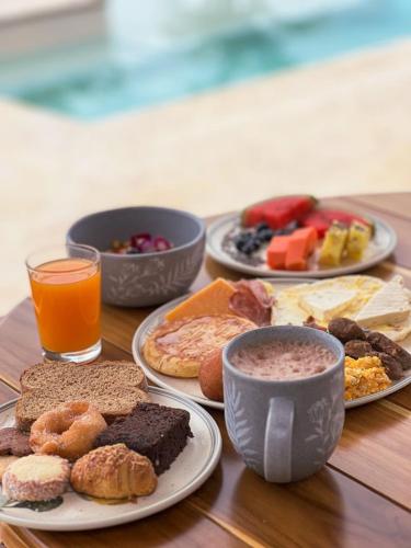 Una mesa de madera cubierta con platos de comida y bebidas. en Fina Estampa Country Hotel - Mayores de 10 años, en Támesis