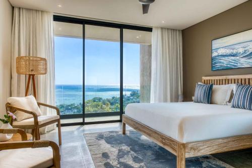 a bedroom with a large bed and large windows at Domaine d'Anbalaba in Ruisseau Créole