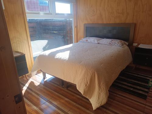 a bedroom with a bed and a large window at Hospedaje Angaroa a 15 min del centro in Puerto Montt