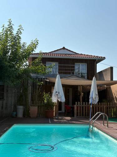 ein Swimmingpool mit zwei Sonnenschirmen vor einem Haus in der Unterkunft Belle villa contemporaine in La Teste-de-Buch