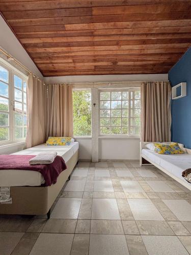 two beds in a room with windows and a wooden ceiling at Paraiso Mar in Búzios