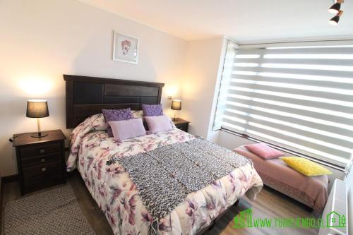 a bedroom with a bed with purple pillows and a window at MPH 204 Departamento en Puerto Varas a pasos del Lago, para 6 personas in Puerto Varas