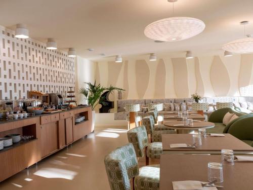 カルヴィにあるHotel & Spa Kasano Calvi - Handwritten Collectionのテーブルと椅子とバーのあるレストラン