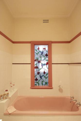 a bathroom with a bath tub and a window at Homely 2-Bed Cottage Near Tenterfield Centre in Tenterfield