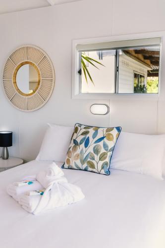 a white bed with a window and a pillow at The Pelican Caravan Park Nambucca Heads in Nambucca Heads