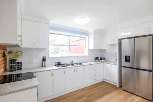 Una cocina con gabinetes blancos y un refrigerador de acero inoxidable. en Country 4-Bed Homestead with Games Room & Views, en Tenterfield
