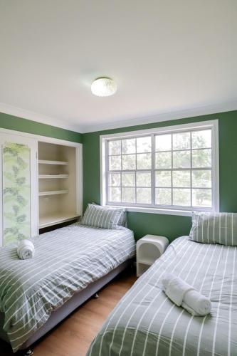 two beds in a room with green walls and windows at Country 4-Bed Homestead with Games Room & Views in Tenterfield
