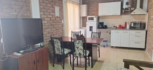 eine Küche mit einem Tisch mit Stühlen und einem TV in der Unterkunft Nuevo Complejo Milena in San Juan