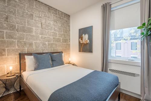 a bedroom with a bed and a brick wall at Modern 2BR - 2 Full Bathrooms - Trendy Location in Montréal