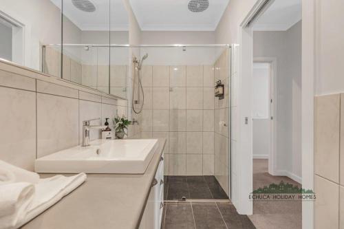 Un baño blanco con lavabo y ducha. en Campaspe Central - Your Central Echuca Escape!, en Echuca