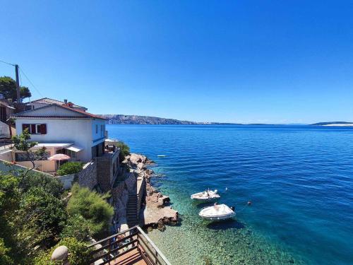 two boats in the water next to a house at Apartment Starigrad - Senj 1 in Starigrad