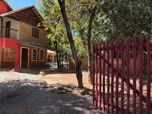 a red fence in front of a house with a tree at Chale com Hidromassagem na Serra do Cipó in Santana do Riacho