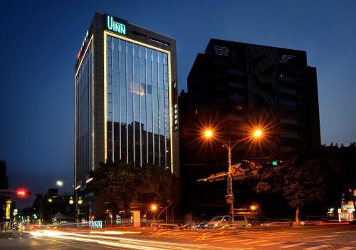 a tall building with a sign on it at night at Uinn Business Hotel-Shihlin in Taipei