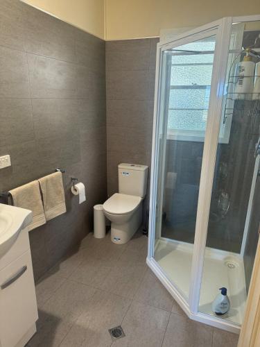 a bathroom with a toilet and a glass shower at The Cottage at Raheen in Mallacoota