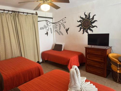 una camera d'albergo con due letti e una tv di Suites Fenicia a Playa del Carmen