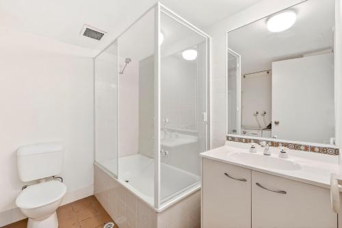 a white bathroom with a toilet and a shower at Villa Sienna Hideaway 2 min walk to tramline in Gold Coast