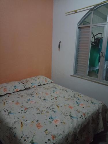 a bed with a floral comforter in a bedroom at Casa Paraense in Belém