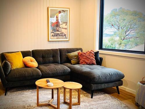 a living room with a couch and a table at Modern Two Bedroom Waterfront Apartment in Jindabyne