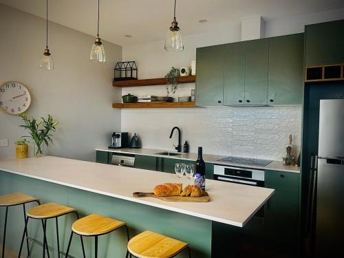 a kitchen with green cabinets and a counter with a plate of bread at Modern Two Bedroom Waterfront Apartment in Jindabyne
