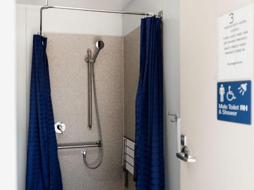 y baño con ducha con cortinas azules. en Breeze Holiday Parks - Mary River, en Marrakai