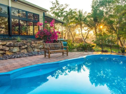 a swimming pool with a bench next to a house at Breeze Holiday Parks - Mary River in Marrakai