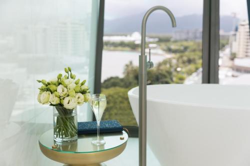 a vase of flowers on a table next to a bath tub at Crystalbrook Riley in Cairns
