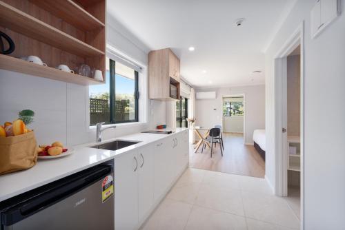 a kitchen with white cabinets and a sink at Albany Oak Motel in Auckland