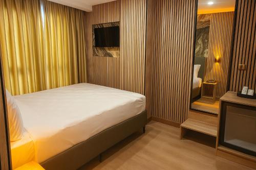 a small bedroom with a bed and a television at Positive Hotel in Arnavutköy
