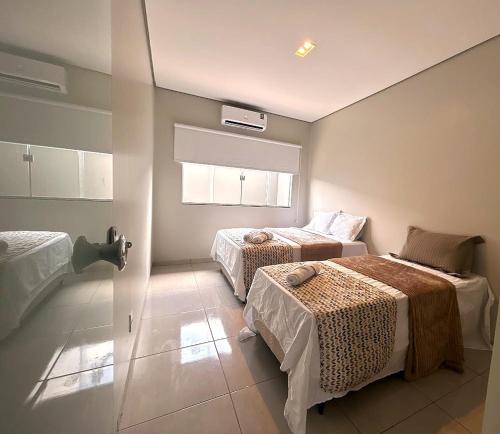 a bedroom with two beds and a window at Casa 03 - Casa com 2 quartos, localizada próximo a rodoviária e aeroporto in Palmas