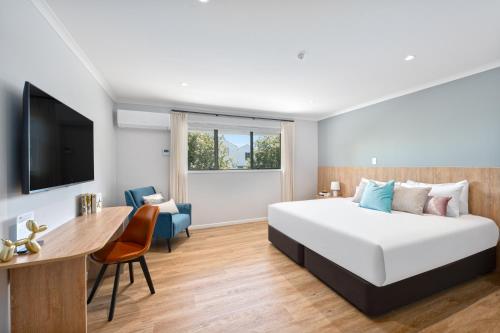 a hotel room with a bed and a desk at Albany Oak Motel in Auckland