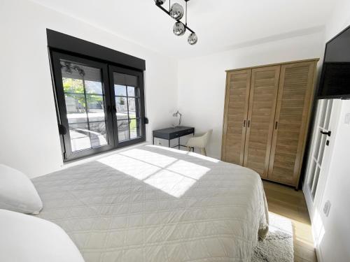 een witte slaapkamer met een groot bed en een raam bij Petite Mansion in Nasicz