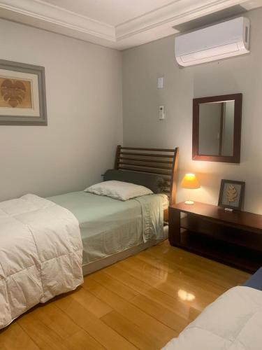 a bedroom with two beds and a desk with a mirror at FamilyHome in Florianópolis