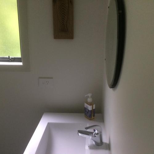 a white bathroom with a sink and a mirror at The Cottage at 95a - self contained, quiet and peaceful in Big Omaha
