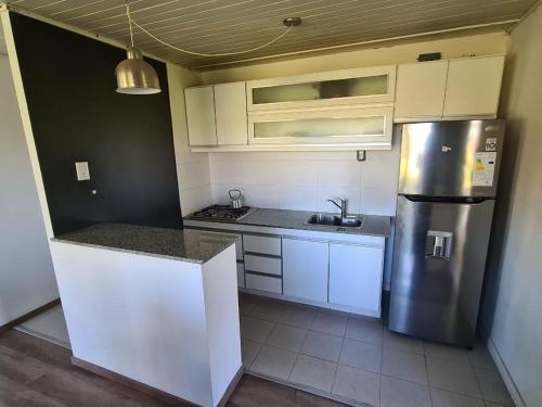 una cocina con nevera de acero inoxidable y armarios blancos en La Colorada, Balneario Marisol - campo, bosque, río y mar, en Oriente