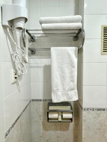 a bathroom with white towels and a towel holder at HS Altet Suites - Alicante Airport in El Alted