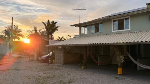 a house with the sun setting behind it at Mares e Flores de Bombinhas in Bombinhas