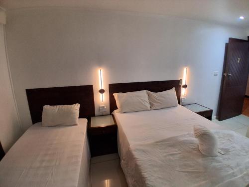 a bedroom with two beds and two lights on the wall at Nadi Airport Transit Hotel in Nadi