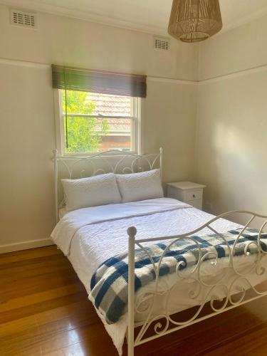 a white bed in a bedroom with a window at Elegant Balwyn Paradise - Spacious Family House in Melbourne's Leafy East in Balwyn