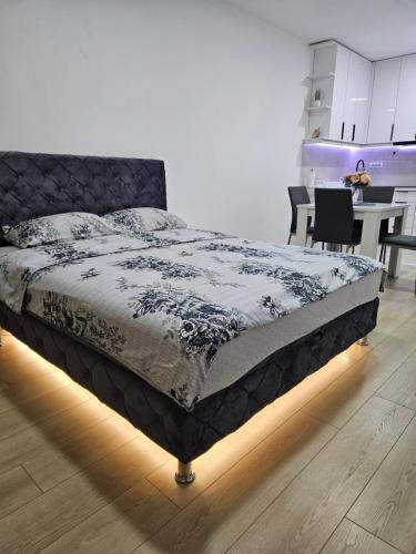 a bed in a room with a table and a kitchen at Miss LUX in Mladenovac