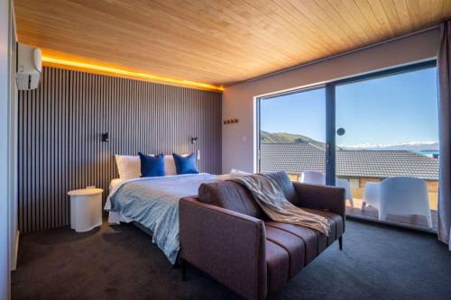 1 dormitorio con cama, sofá y ventana grande en Tekapo Haven with Deck and Stargazing Sky, en Lake Tekapo