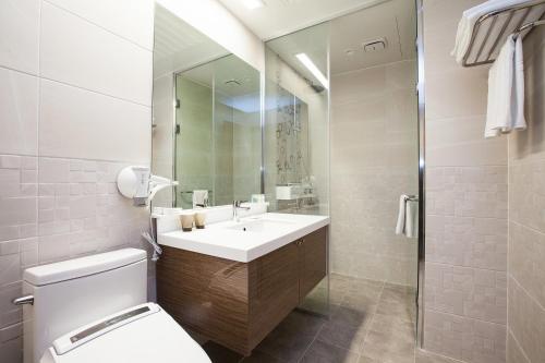 W łazience znajduje się umywalka, toaleta i lustro. w obiekcie YOUUS Hotel w mieście Seogwipo