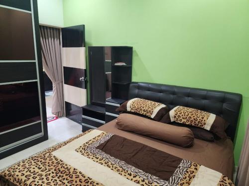 a bedroom with a bed with a black leather headboard at HOMESTAY RIZQI - MUS LIM Only in Air Molek