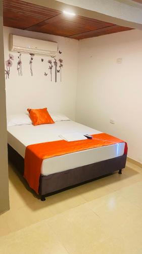 a bedroom with a bed with an orange pillow on it at WAYANAY TAYRONA ECO HOSTEL in El Zaino