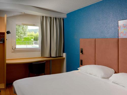 a bedroom with two beds and a desk and a window at ibis Aix en Provence in Aix-en-Provence