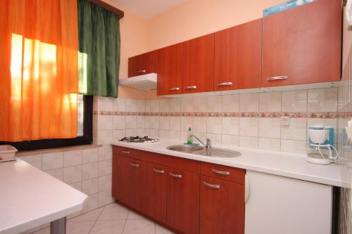 a kitchen with a sink and wooden cabinets and a window at Apartment Pomer 7374a in Pomer