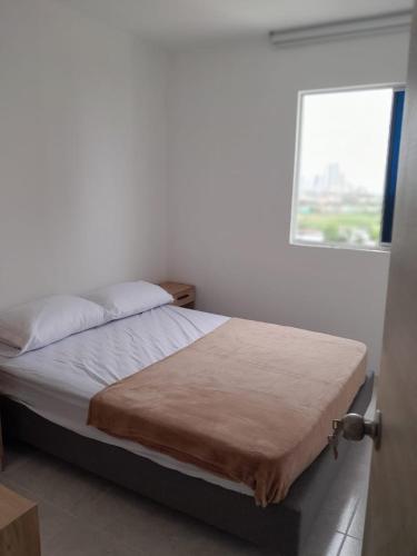 a bed in a white room with a window at Beautiful apartment 5 minutes from the Historic Center in Cartagena de Indias