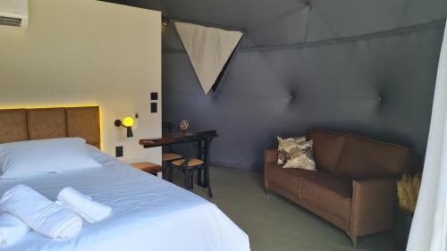 a bedroom with a bed and a couch and a chair at Domo da Montanha in Monte Verde