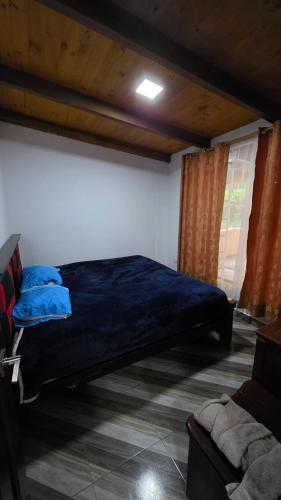 a bedroom with a bed with blue pillows in it at Cabaña rústica con encanto y luces cálidas para noches inolvidables in Apuela